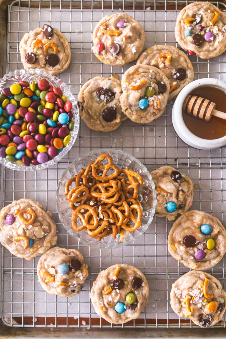 Overhead image of Kitchen Sink Cookies on a cooling rack with honey, pretzels, m&ms