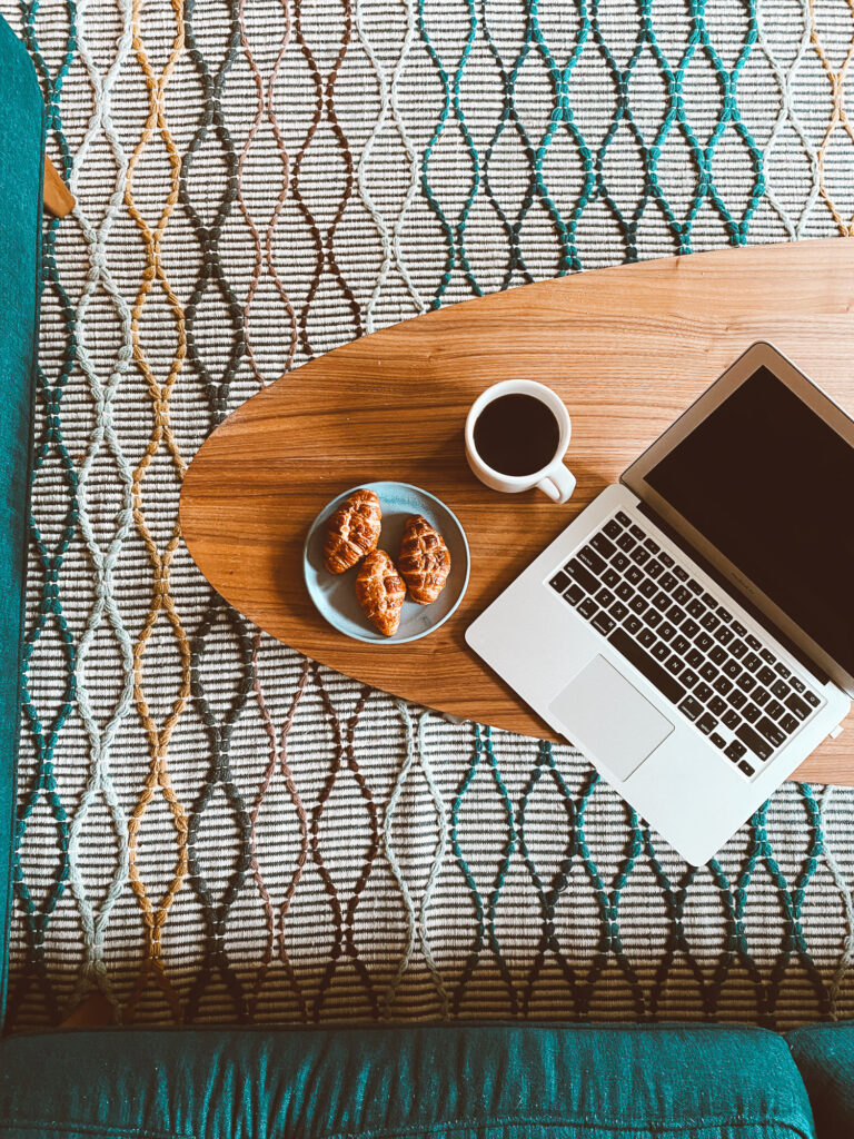 overhead shot of the coffee table, croissants, coffee and an open laptop