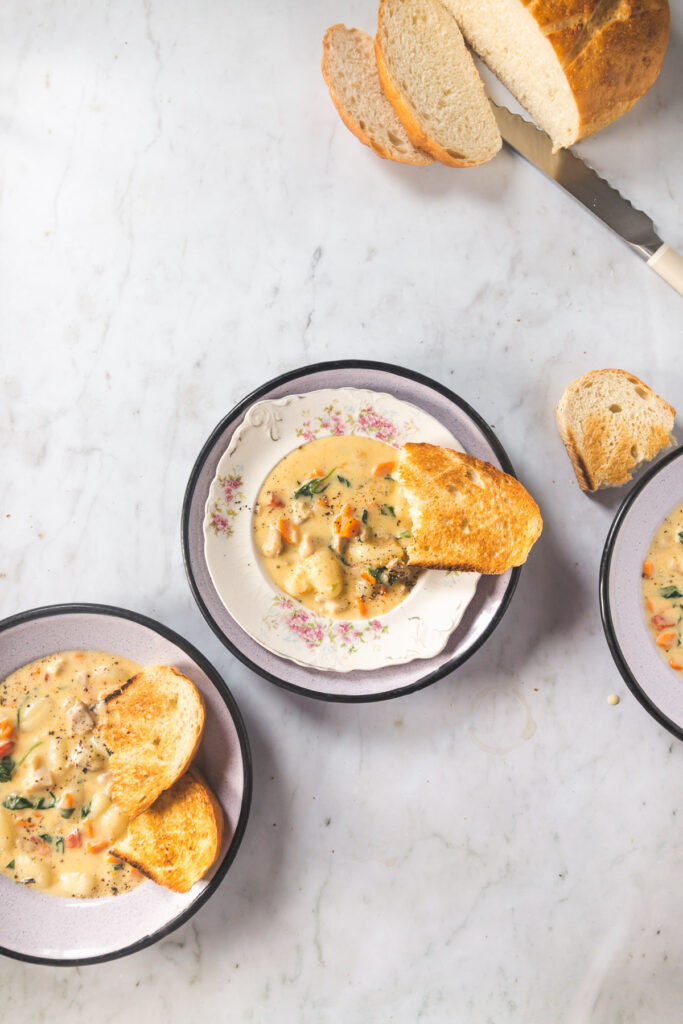 Overhead shot of 3 bowls of soup with crusty bread on the side