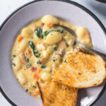 Overhead shot of Creamy Chicken Gnocchi Soup with crusty bread dipped in