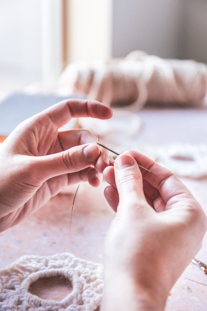 hands sewing in the tinsel into the yarn