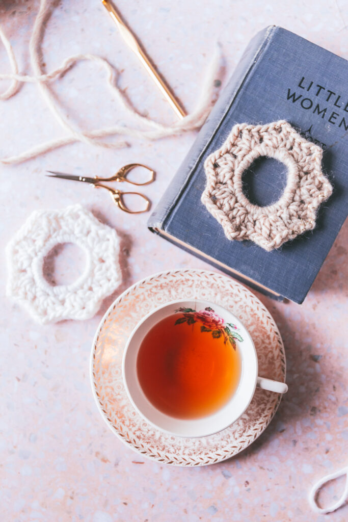 overhead of two crochet scrunchies with a cup of tea and the book Little Women