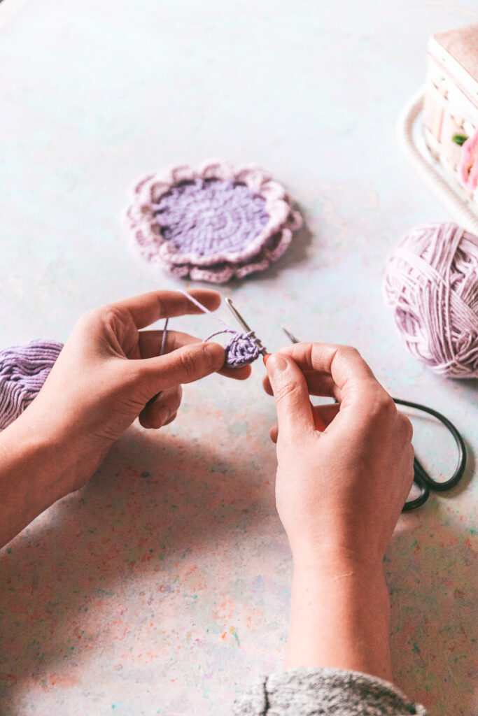 Hands crocheting with purple and lavender yarn