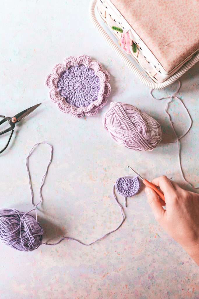 Hands crocheting with purple and lavender yarn